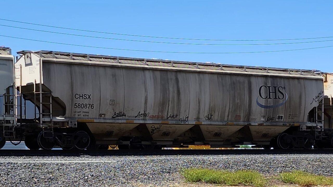 A 4 BAY COVERED HOPPER SHOWING SOME EXCESSIVE STREAKS ON ITS SIDES FROM LOADS IT HAS CARRIED